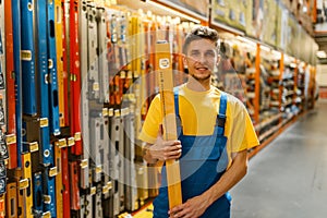 Male builder with building level in hardware store