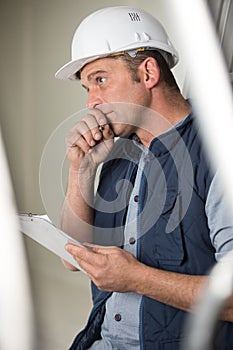 male builder with clipboard in deep contemplation