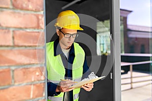 male builder with clipboard looking out window