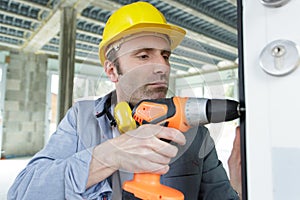 male builder drilling wood frame