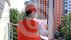 Male builder in hardhat standing on the construction site while looking at the drawings. Business, building, industry