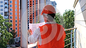 Male builder in hardhat standing on the construction site while looking at the drawings. Business, building, industry