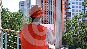 Male builder in hardhat standing on the construction site while looking at the drawings. Business, building, industry