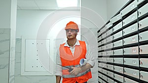 Male builder in helmet holding drawing and walkie-talkie walking in the entrance to a construction site. Business