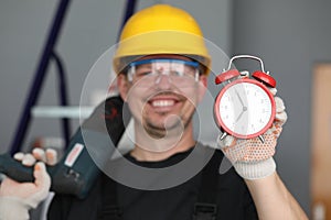 Male builder helmet laughing showing alarm clock