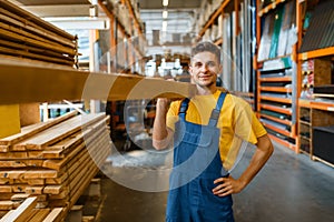 Male builder holds wooden boards in hardware store photo