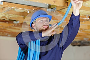 Male builder installing pipes in ceiling
