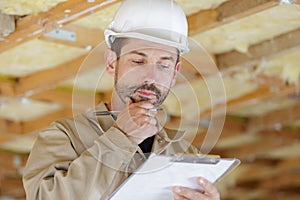 male builder looking at clipboard photo