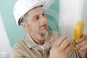 male builder measuring voltage in electrical wall recepticle