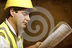 Male builder site foreman reading architectural industrial plans