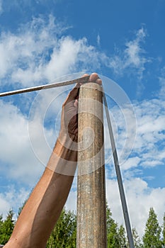 Male Builder with a tape measure on a real construction site in nature. Measures the distance between the posts with a
