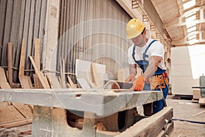 Male builder using industrial woodworking equipment in workshop