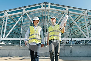 Male builders go forward on roof of construction site. Building, development, teamwork and people concept