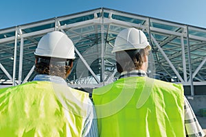 Male builders on roof of construction site,back view. Building, development, teamwork and people concept