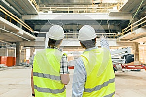 Male building workers working at construction site, back view. Building, development, teamwork and people concept