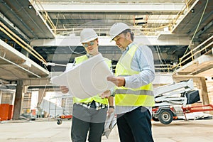 Male building workers working at construction site, builders looking in blueprint. Building, development, teamwork and people