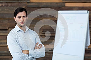 Male business executive standing with arms crossed in office