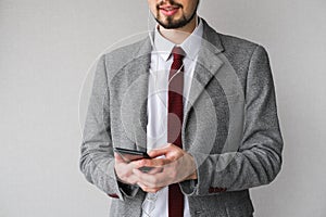 Male businessman in a gray suit listens to music on the phone. male boss communicates on the phone through headphones.