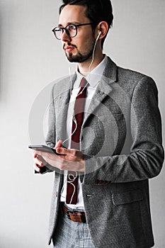 Male businessman in a gray suit listens to music on the phone. male boss communicates on the phone through headphones.