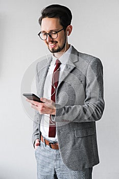 Male businessman in a gray suit listens to music on the phone. male boss communicates on the phone through headphones.