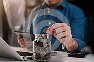 Male businessman hand puting coins in glass for saving money. concept finance and accounting.