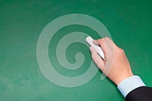 Male businessman hand in suit writing on a blackboard with white