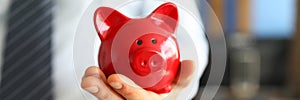 Male businessman hold in hand red little piggybank