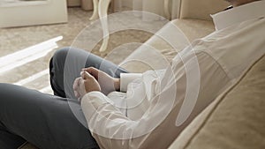 Male businessman sitting in trousers and shirt on the couch with his hands folded