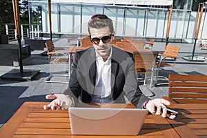 Male businessman or worker in black suit at the table with smartphone