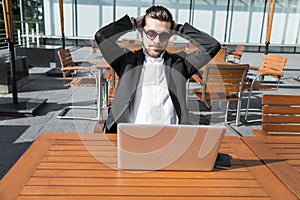 Male businessman or worker in black suit at the table with smartphone