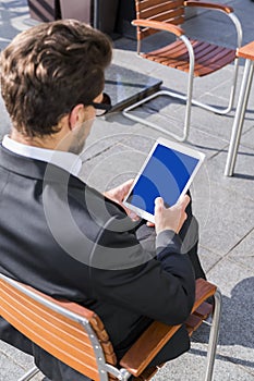 Male businessman or worker in black suit with tablet sitting on chair