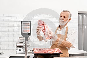 Male butcher demonstrating meat in supermarket.