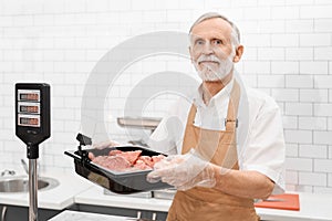 Male butcher demonstrating meat in supermarket.