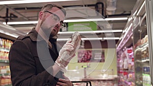 The male buyer chooses and sniffles frozen fish in supermarket