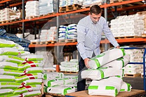 Male buyer storing fertilizer bags on trolley in hardware store