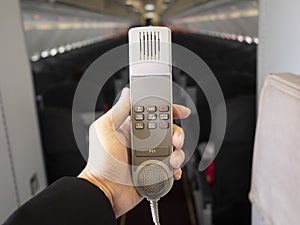 Male cabin crew holding interphone in aircraft cabin.