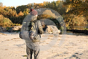 Male camper with backpack and sleeping bag in wilderness.