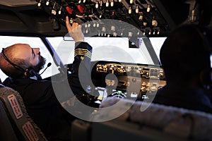 Male captain pushing buttons to start power on dashboard control