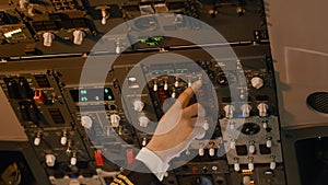 Male captain pushing dashboard buttons to start airplane engine
