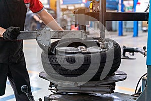 A male car mechanic changing tires and balancing car wheel on balancer at auto repair shop for the auto industry. Automobile