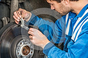 Male Car Mechanic Examining Brake Disc With Caliper