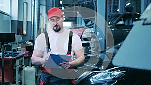 Male car mechanic taking notes at an auto repair shop