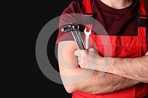 Male car mechanic with tools on black background, closeup