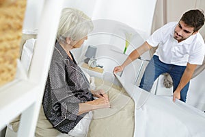 male caring nurse helping sick elderly woman