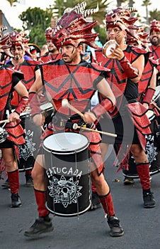Male carnival drummer in red costume marching and playing.