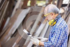 Male carpenter in a construction workshop, using a digital tablet