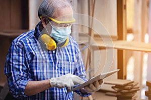 Male carpenter in a construction workshop, using a digital tablet