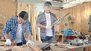 Male carpenter cutting some wood in a table saw. Young carpenter using measuring tape at work