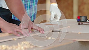 Male carpenter cutting some wood in a table saw. Young carpenter using measuring tape at work