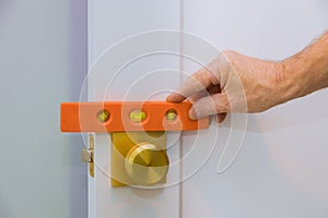 Male carpenter fixing lock in door with home